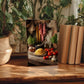 a wooden table with a framed photograph of a kitchen scene, including a variety of fresh produce, herbs, and cooking utensils.