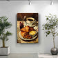 a painting of a breakfast scene with a croissant, butter, and jam on a plate, displayed on a wall in a room with two potted plants.